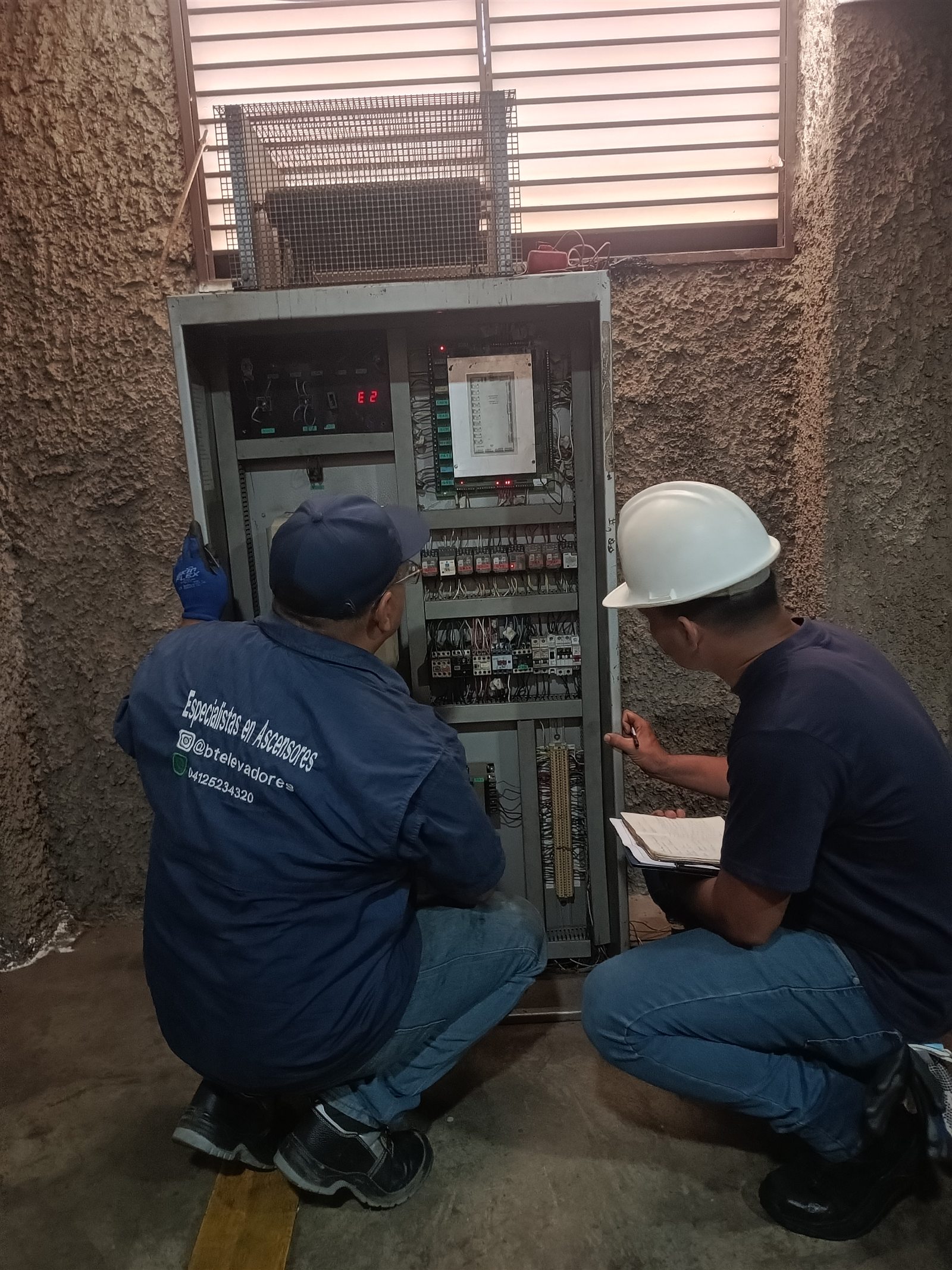 Técnicos inspeccionando el tablero de control de un ascensor